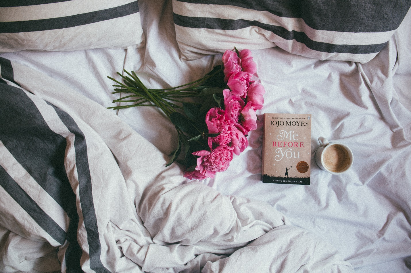 Coffee book and flowers in bed