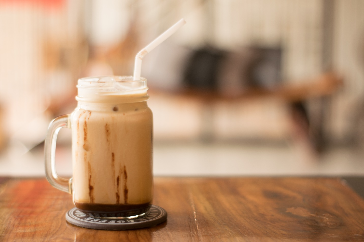 Cold coffee in a mason jar with a plastic straw