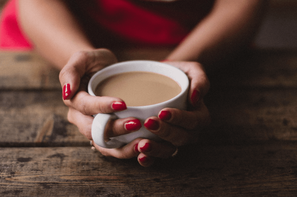 Woman in red holding a cup of coffee with both hands