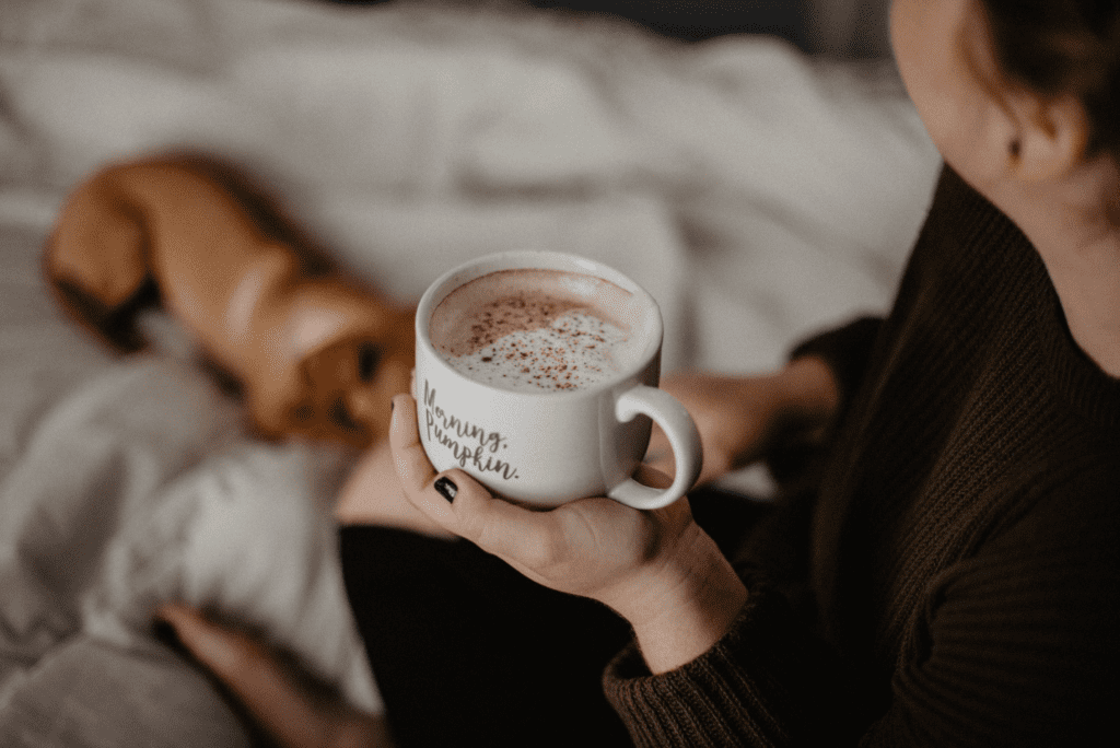 Woman lying in bed holding a cup of coffee